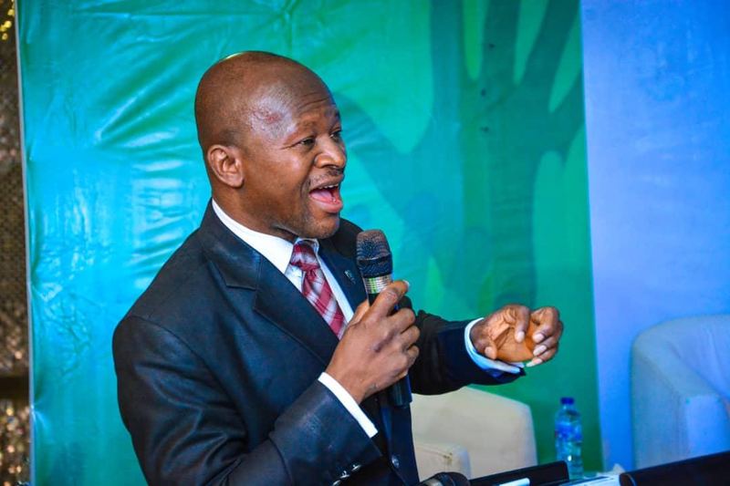A guest speaker in a suit speaks into a microphone.